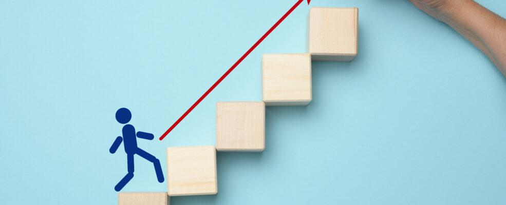 A figure walking up wooden blocks like stairs as symbolism for business growth due to following the ROI of a Strong Brand