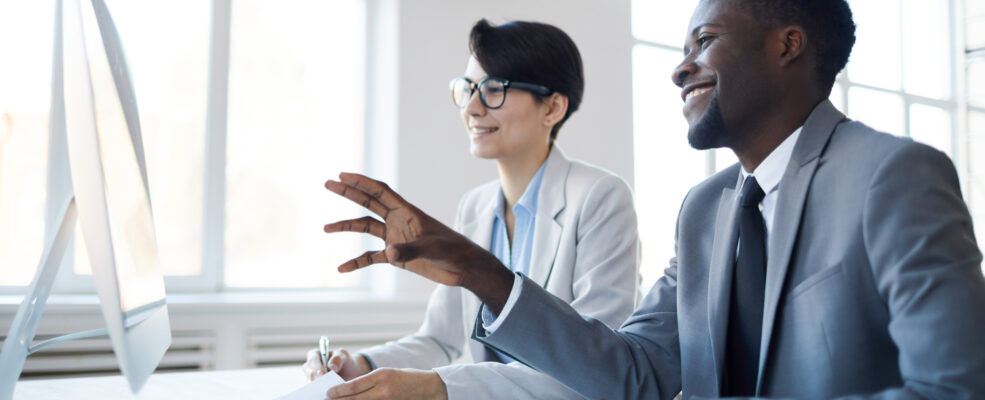 Two colleagues looking happy as they look at a screen to illustrate happy interactions with clients