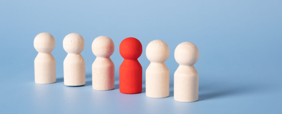 Six wooden figurines, one is painted red. Illustrates your brand standing out