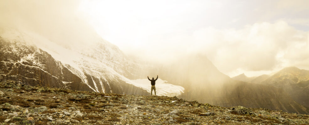 A man standing triumphantly on a mountain because his brand out-competed his competitors