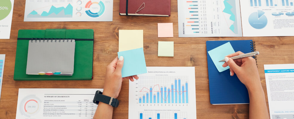 A person makes marketing plans with stick notes and graphs