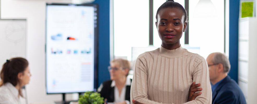 A businesswoman stands, facing the camera and smiling. She is meant to represent a satisfied, high-value client
